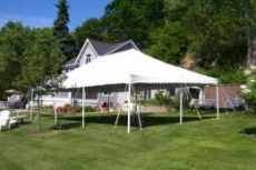 20X20 White pole tent with house and trees in the background
