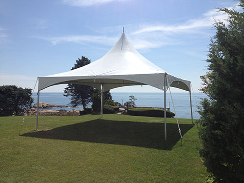 20x20 White Wedding High Peak tent setup by water with a blue sky background
